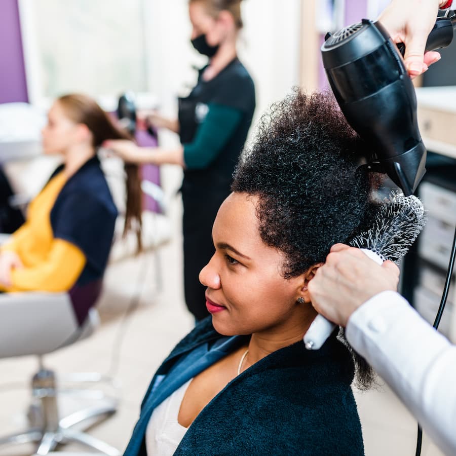 A hairdresser dries a woman's hair in a modern hair salon