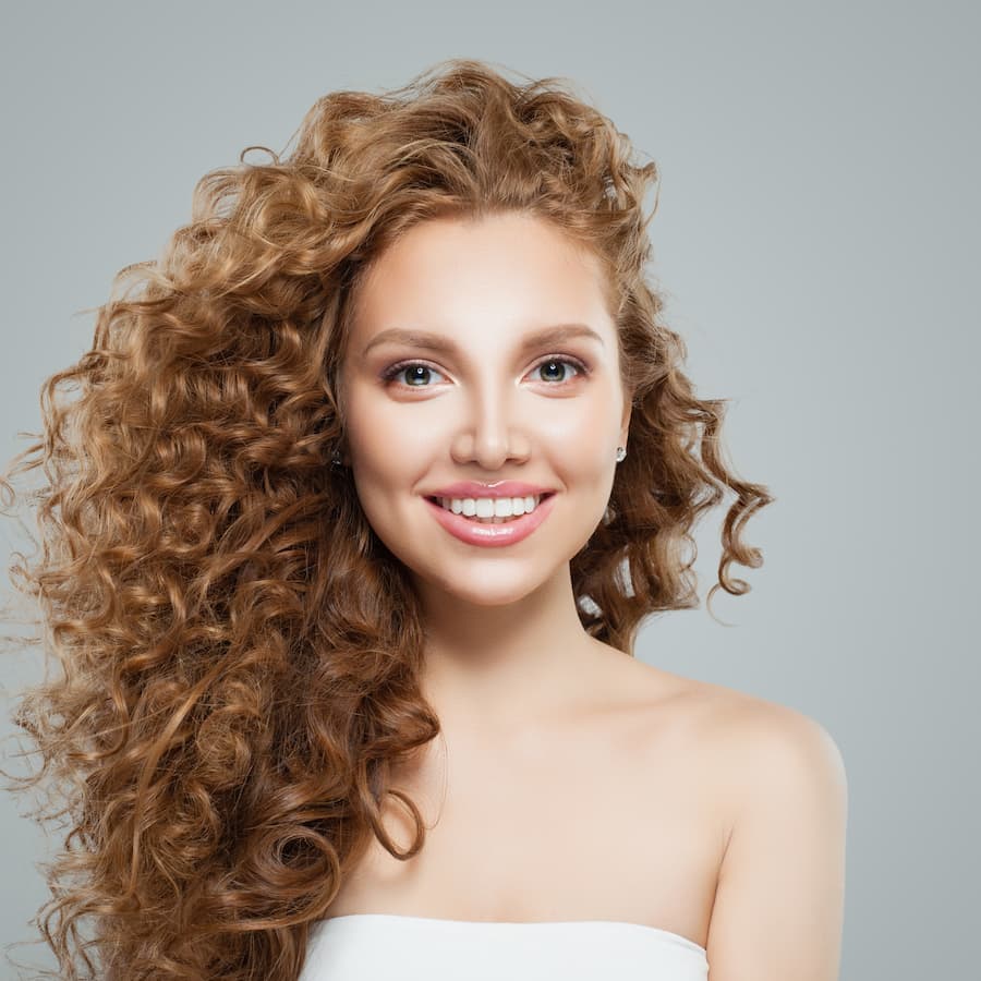 Happy redhead woman with long healthy curly hair